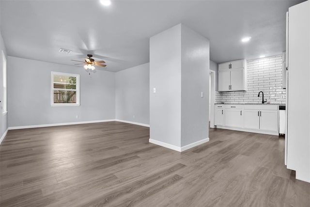 unfurnished living room featuring ceiling fan, sink, and wood-type flooring