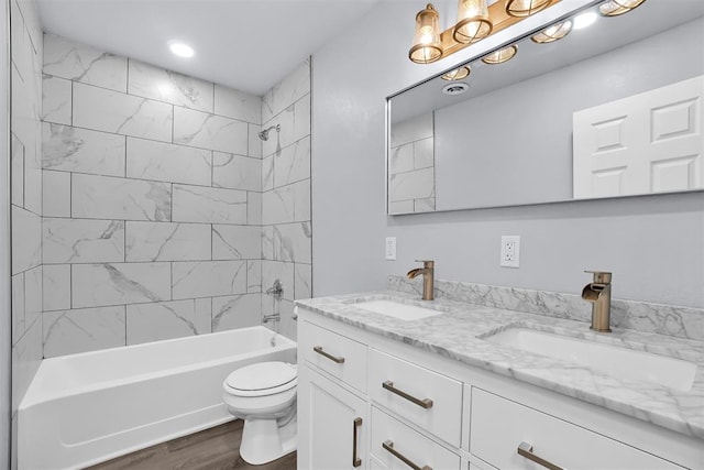 full bathroom with hardwood / wood-style floors, tiled shower / bath combo, toilet, and vanity