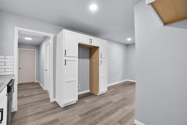 kitchen with baseboards, white cabinetry, light wood-style flooring, and dishwasher