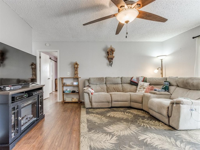 living room featuring ceiling fan, dark hardwood / wood-style flooring, and a textured ceiling