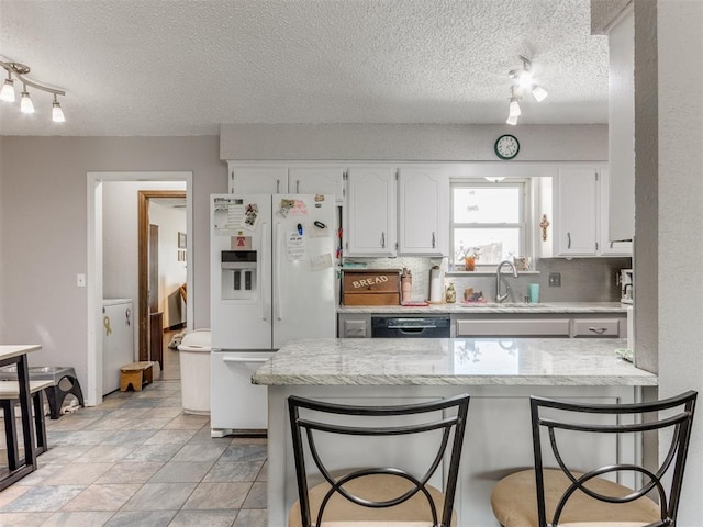 kitchen featuring kitchen peninsula, white cabinetry, white fridge with ice dispenser, and sink