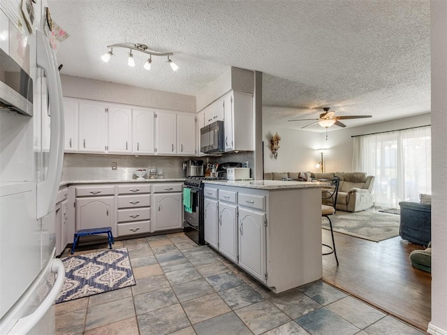 kitchen with white cabinetry, light hardwood / wood-style flooring, ceiling fan, and black appliances