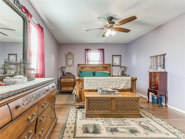 bedroom featuring ceiling fan, light hardwood / wood-style flooring, and a textured ceiling