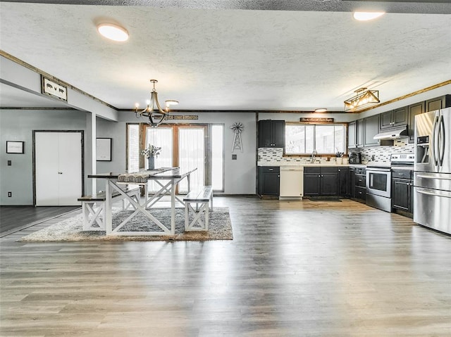 kitchen featuring sink, stainless steel appliances, tasteful backsplash, a textured ceiling, and hardwood / wood-style flooring