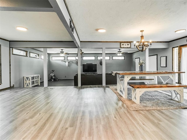 miscellaneous room featuring ceiling fan with notable chandelier, a textured ceiling, light hardwood / wood-style flooring, and crown molding