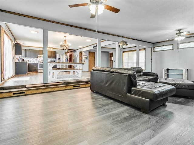 living room with crown molding, ceiling fan with notable chandelier, and hardwood / wood-style flooring