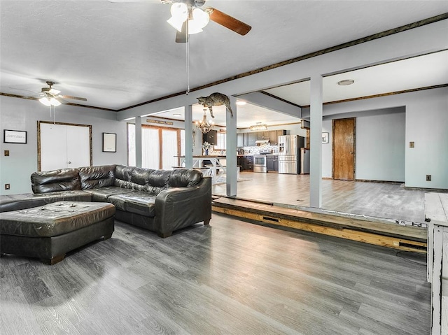 living room with hardwood / wood-style floors, ceiling fan with notable chandelier, and crown molding