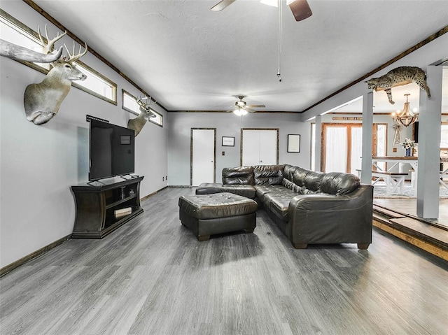 living room featuring wood-type flooring, ceiling fan with notable chandelier, and ornamental molding