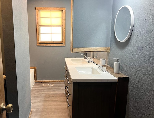 bathroom with hardwood / wood-style floors, vanity, and a bathing tub