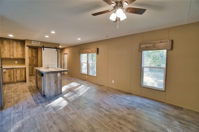 kitchen with a barn door, a center island, a healthy amount of sunlight, and light hardwood / wood-style floors