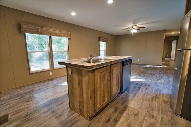 kitchen with appliances with stainless steel finishes, ceiling fan, dark wood-type flooring, sink, and a center island with sink