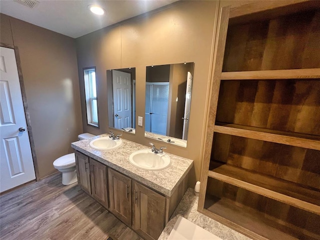 bathroom with walk in shower, hardwood / wood-style floors, vanity, and toilet