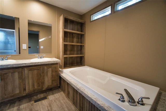 bathroom with a washtub, vanity, and wood-type flooring