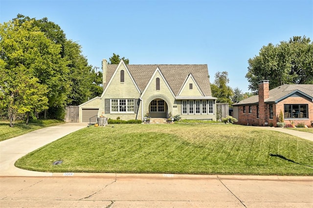 tudor home with an outbuilding, a front lawn, and a garage