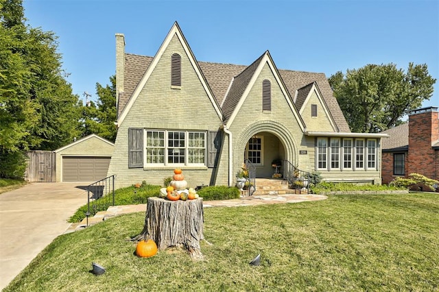 english style home with a garage, an outbuilding, and a front lawn