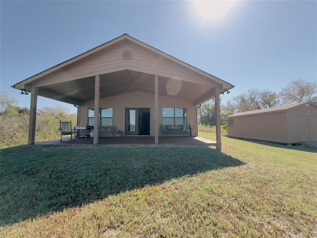 back of house featuring a storage shed, a patio, and a lawn