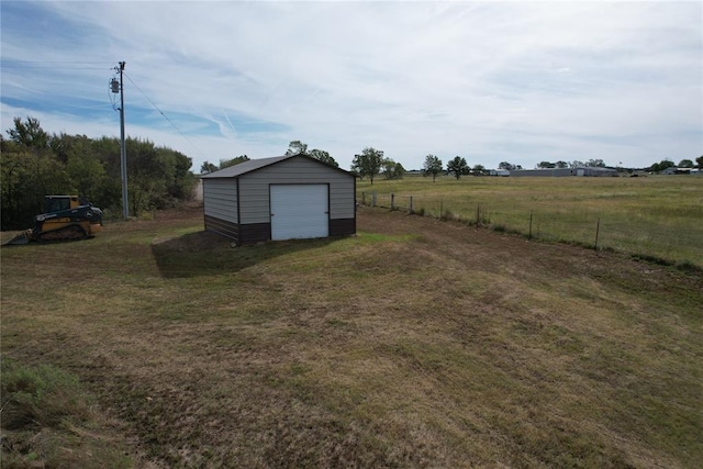 view of yard with a garage, an outbuilding, and a rural view