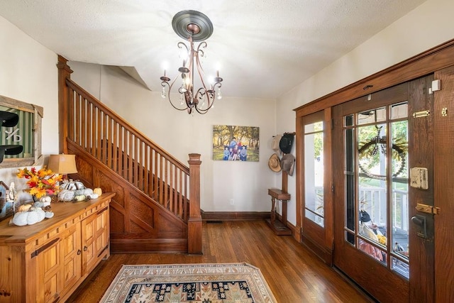 foyer featuring a textured ceiling, dark wood-type flooring, and an inviting chandelier