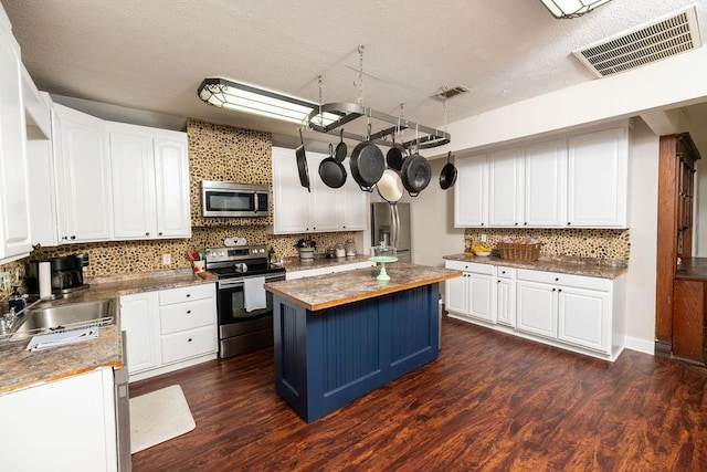 611 Wichita Ave, Devol, OK 73531 - kitchen featuring appliances with stainless steel finishes, a sink, decorative backsplash, white cabinetry, and a kitchen island