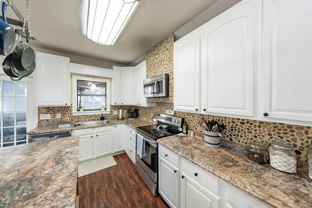 611 Wichita Ave, Devol, OK 73531 - kitchen with stainless steel appliances, decorative backsplash, dark wood-style floors, and white cabinetry