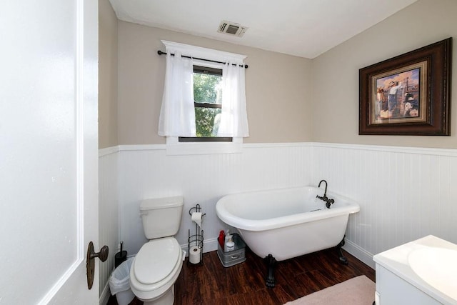 bathroom with hardwood / wood-style floors, toilet, a bathing tub, and vanity