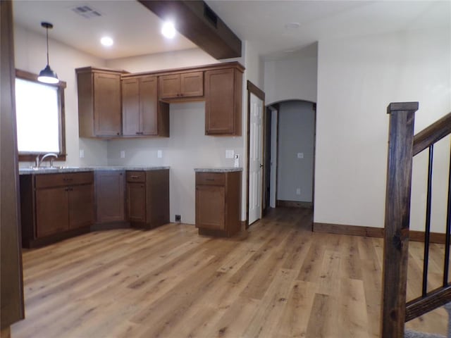 kitchen with light hardwood / wood-style floors, light stone counters, and hanging light fixtures