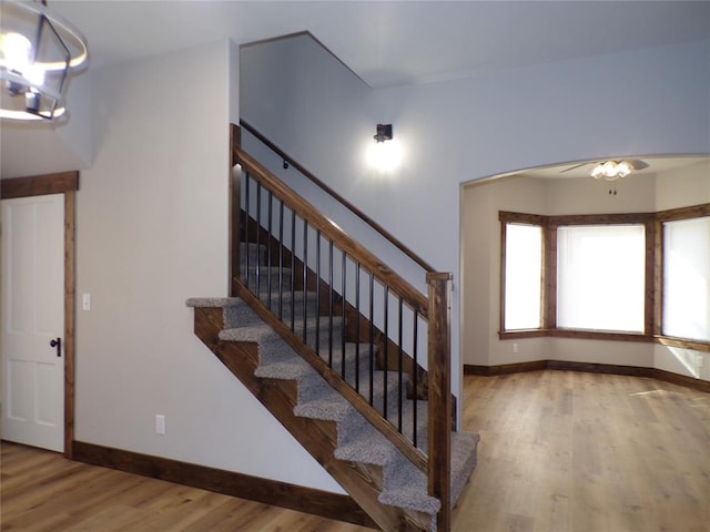 stairs with wood-type flooring and a chandelier