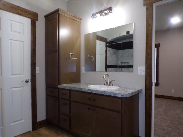 bathroom with a tile shower and vanity