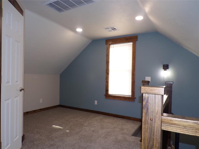 bonus room with light colored carpet and vaulted ceiling