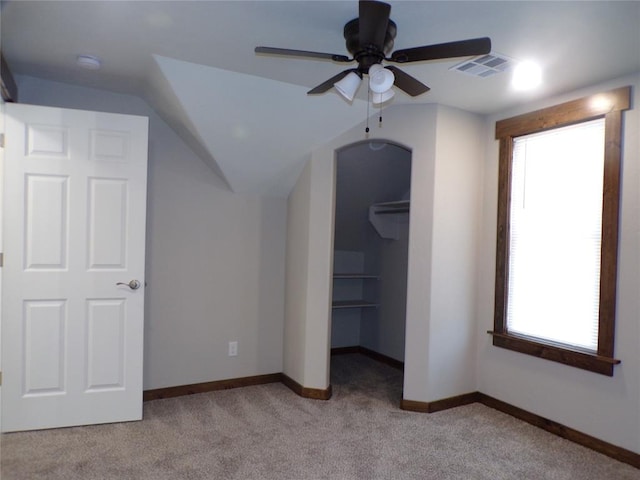 unfurnished bedroom featuring light colored carpet, ceiling fan, a spacious closet, a closet, and lofted ceiling