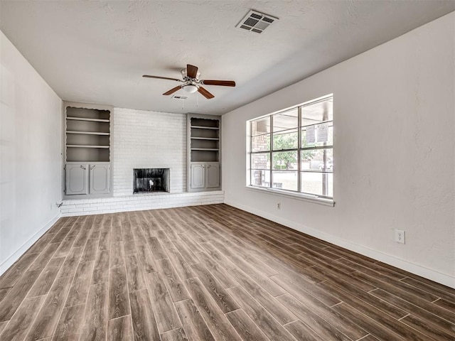 unfurnished living room featuring ceiling fan, a fireplace, built in features, and dark hardwood / wood-style floors