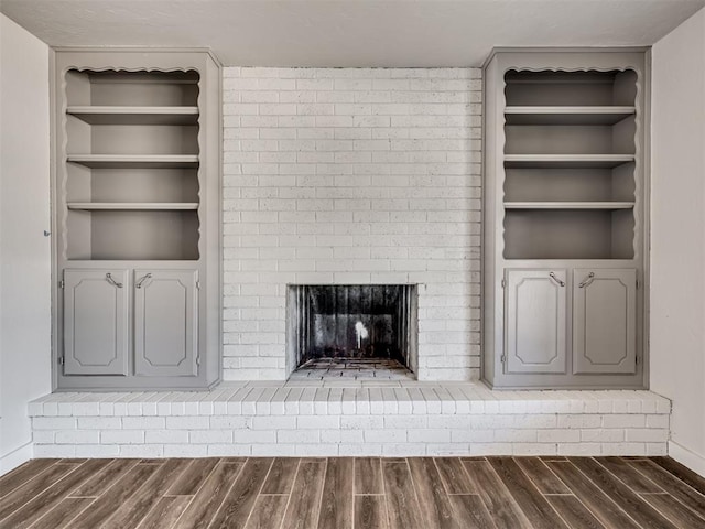 unfurnished living room with built in shelves, a fireplace, and dark hardwood / wood-style floors