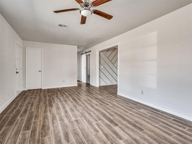 spare room featuring hardwood / wood-style floors, ceiling fan, and a barn door