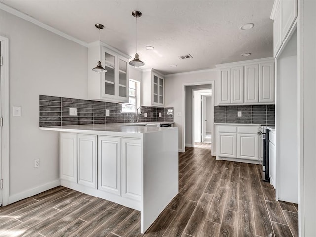 kitchen featuring white cabinets, kitchen peninsula, crown molding, and dark wood-type flooring