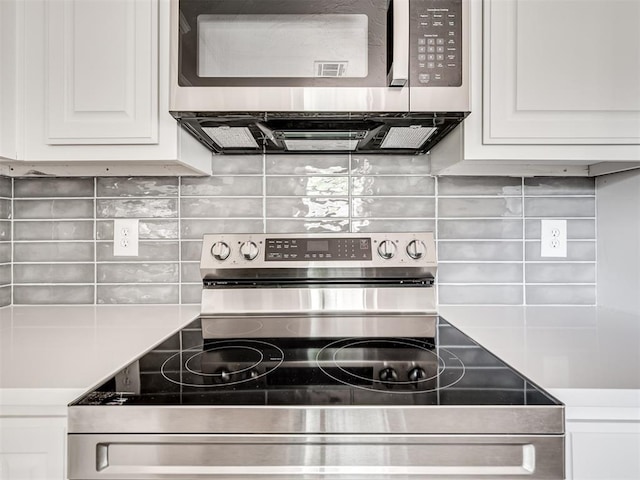 kitchen with white cabinets, appliances with stainless steel finishes, and tasteful backsplash