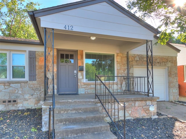 view of exterior entry with a garage and covered porch