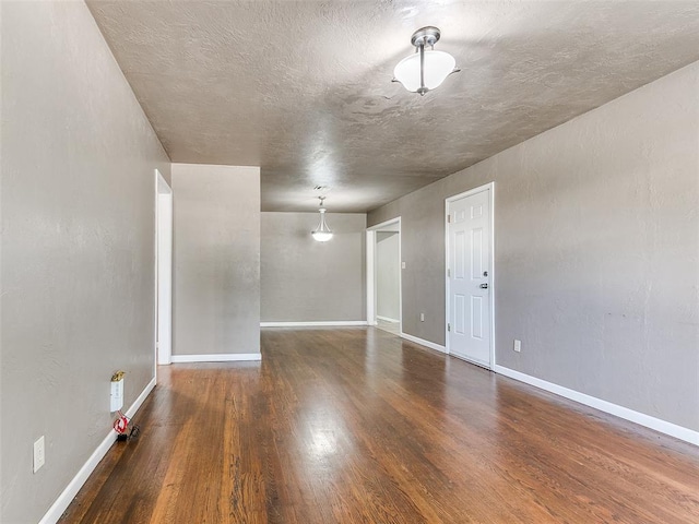 spare room with a textured ceiling and dark wood-type flooring