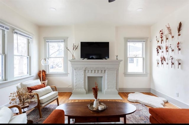 living room with light hardwood / wood-style flooring, a brick fireplace, and plenty of natural light