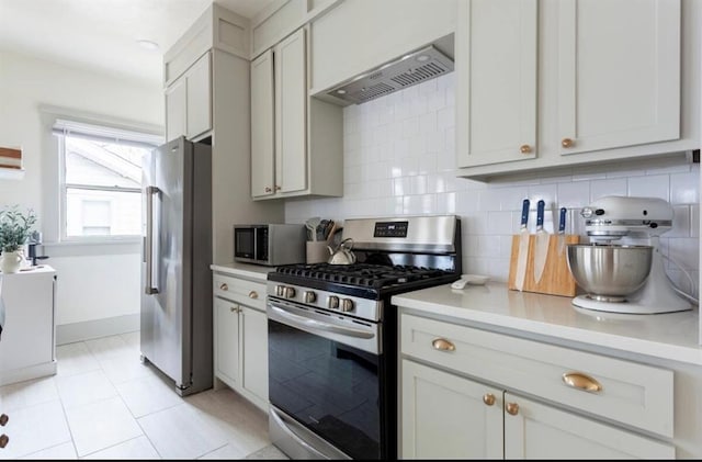 kitchen featuring white cabinetry, backsplash, appliances with stainless steel finishes, light tile patterned flooring, and custom exhaust hood