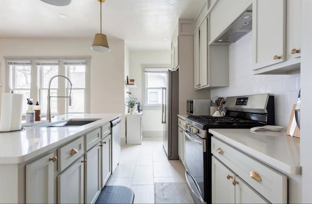 kitchen with decorative backsplash, appliances with stainless steel finishes, gray cabinetry, wall chimney range hood, and pendant lighting