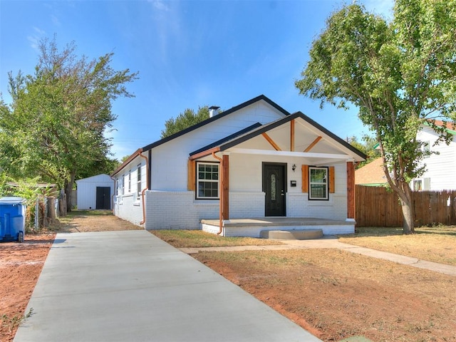 view of front of home with covered porch and a storage shed