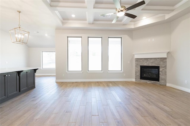 unfurnished living room with light wood finished floors, beam ceiling, coffered ceiling, and ceiling fan with notable chandelier