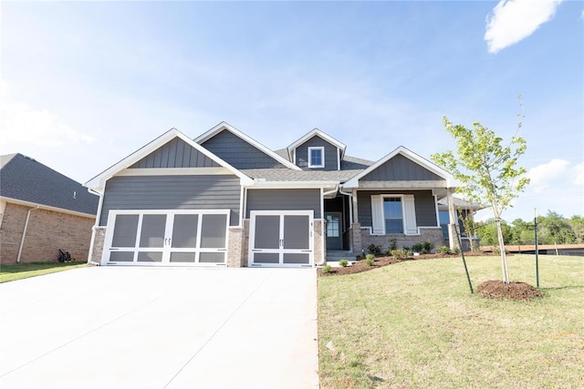 craftsman inspired home featuring a garage, board and batten siding, a front lawn, and concrete driveway