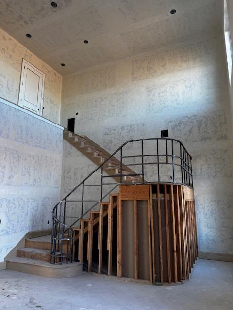 stairway with a towering ceiling and concrete floors