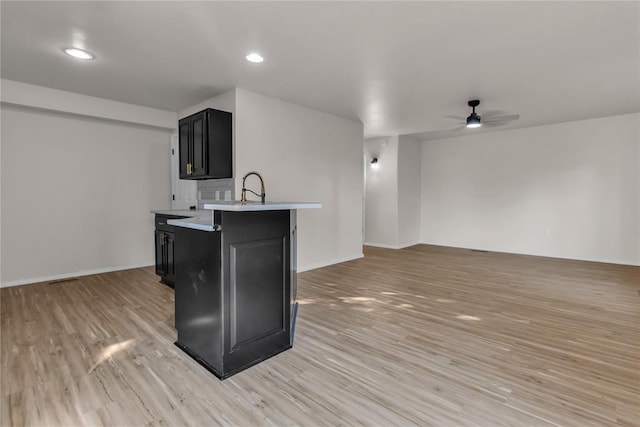 kitchen with kitchen peninsula, light hardwood / wood-style floors, ceiling fan, and sink