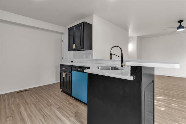 kitchen featuring sink, stainless steel dishwasher, ceiling fan, light wood-type flooring, and a breakfast bar area