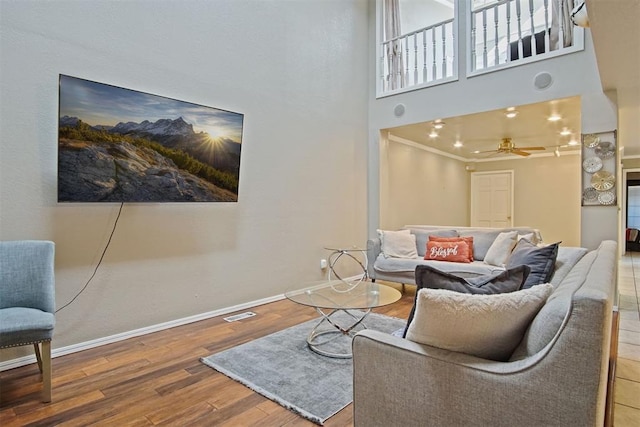 living area featuring a high ceiling, ceiling fan, and hardwood / wood-style flooring