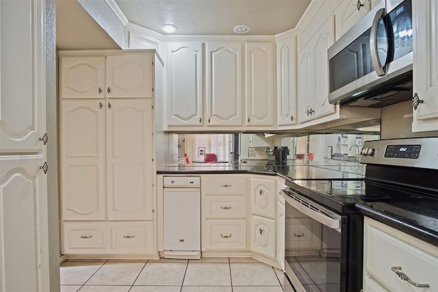 kitchen with appliances with stainless steel finishes, white cabinetry, light tile patterned flooring, and a textured ceiling