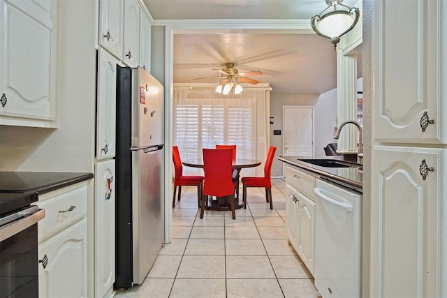 kitchen with stainless steel appliances, light tile patterned floors, ceiling fan, sink, and white cabinetry