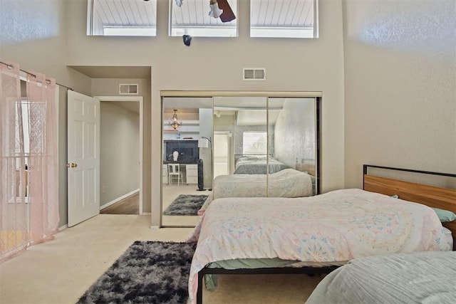 carpeted bedroom featuring a high ceiling and a closet